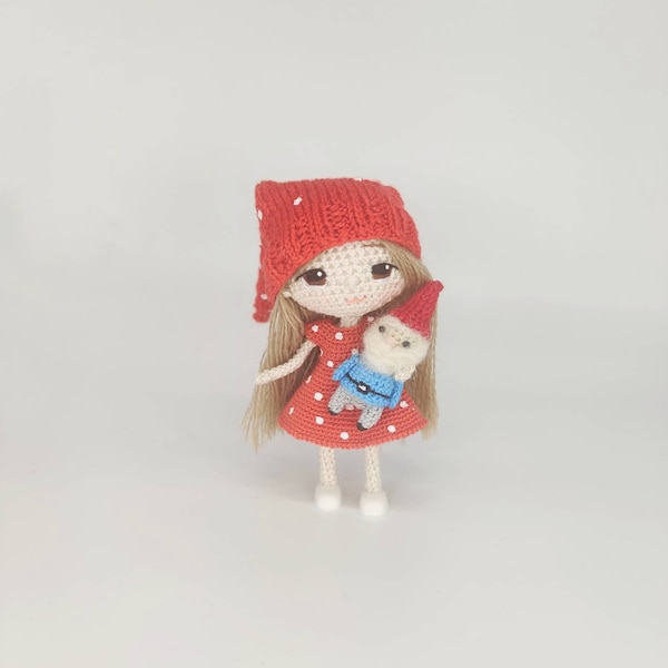 маленькая вязаная крючком кукла в шапочке в новогоднем красном платье с рассыпающимся гномом в подарок на Рождество