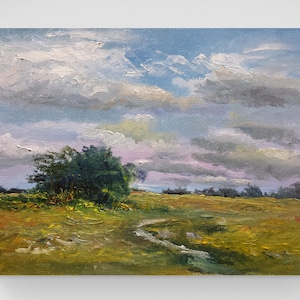 May include: Oil painting depicting a landscape with a field of yellow and green grass, a small stream, and a cluster of trees. The sky is blue with fluffy white and grey clouds. The artwork is on a canvas.
