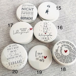 May include: A collection of white, round magnets with various black text and red heart designs. One magnet reads "Love is in the air." Another says "You are my favorite person."