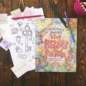 May include: A children's book titled "The Berry Patch" by Elise Monsour Puckett, illustrated by Teja Riley. The cover features a colourful illustration of a berry patch with fairies and a mouse.