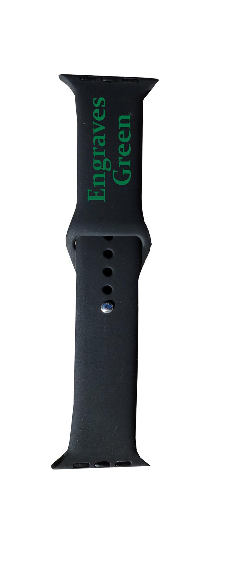 以下が含まれることがあります： 黒いシリコン製の時計バンド。緑色の文字で「Engraves Green」と書かれています。バンドはクラシックなデザインで、複数の調整穴とシルバー色のピンが付いています。