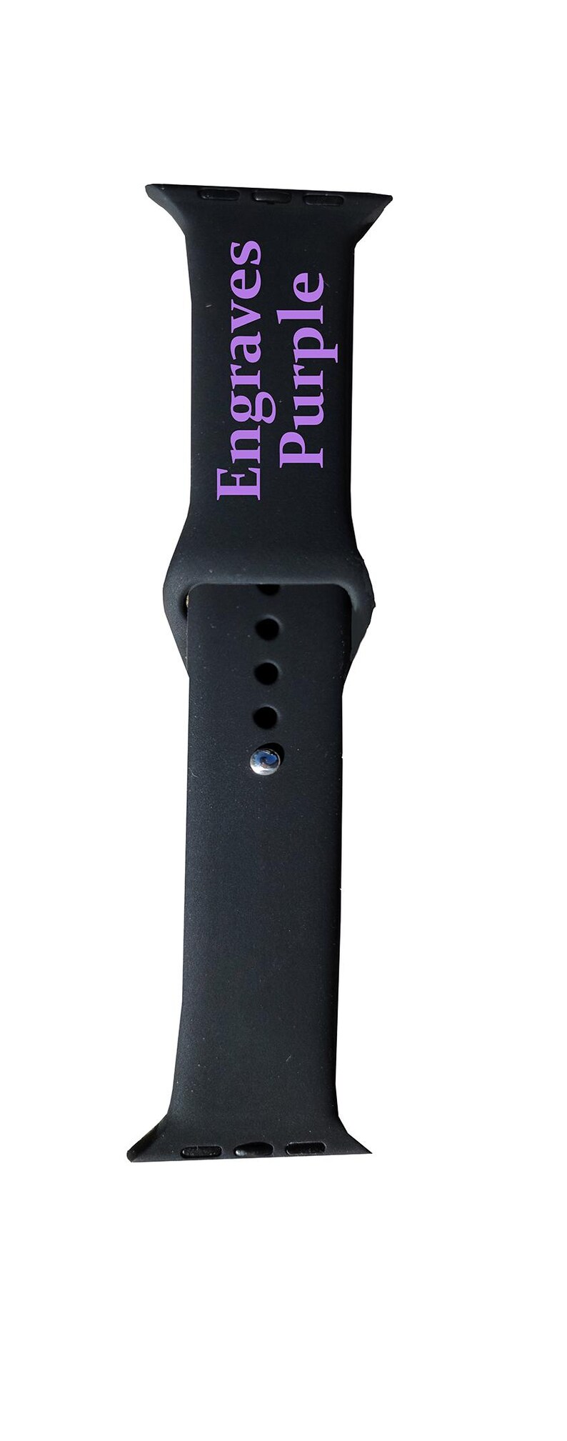 以下が含まれることがあります： 黒色の時計バンドで、ラベンダー色の「Engraves Purple」の文字が入っています。バンドはクラシックなデザインで、複数の調整穴とシルバー色のバックルが付いています。
