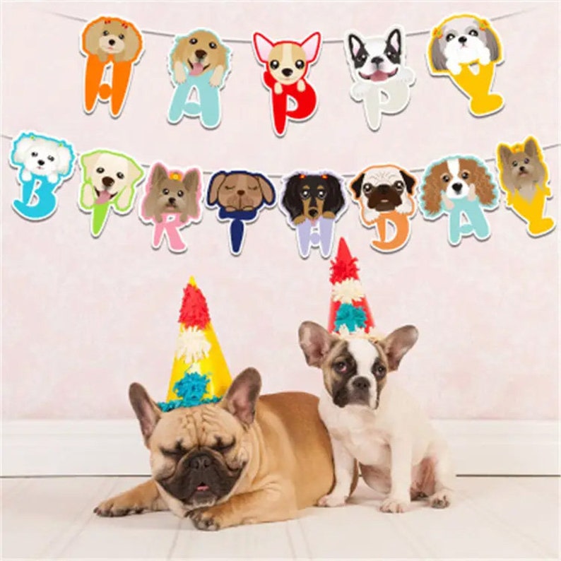 Puede incluir: Una pancarta colorida con tem&aacute;tica de perros con las palabras "Feliz cumplea&ntilde;os" y varias razas de perros, incluyendo un pug, un dachshund y un chihuahua. Dos bulldogs franceses llevan gorros de fiesta delante de la pancarta.