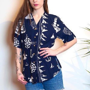 May include: A navy blue short-sleeved button-up shirt with a white nautical print featuring boats, anchors, and compasses.
