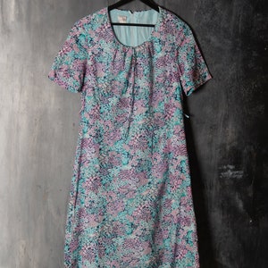 May include: A blue and pink floral print dress with short sleeves and a round neckline. The dress has a tie at the neckline and hangs to the knees.