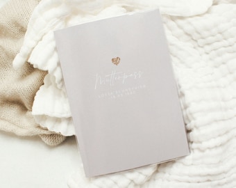 May include: A light gray baby record book with a gold glitter heart and the text "Mutterpass" in white script. The text "LOTTA SCHNEIDER" and "18.06.1993" is also printed in white.