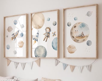 May include: Set of three watercolor prints featuring an astronaut, planets, and a rocket ship. The prints are framed in natural wood and have a white background.