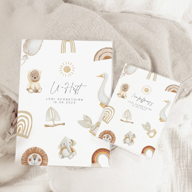 May include: Two white cards with a light brown background and illustrations of animals and rainbows. The text on the cards reads "U-Haft Leni Schneydrin 16.06.2023" and "Willkommen Leni Schneydrin 16.06.2023".