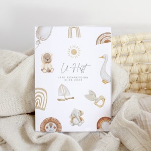 May include: A white card with a brown and white bear, a sun, a sailboat, a bird, an elephant, a lion, and a rainbow. The card says "U-H&auml;tt" and "LENI SCHNEYDIRN 16.06.2023".