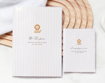May include: Two white booklets with thin vertical beige stripes, each featuring a small watercolor lion illustration. The larger booklet displays the text U-Heft, Navid Schneydyrn, and 23.09.2026. The smaller booklet displays Impfpass, Navid Schneydyrn, and 23.09.2026.