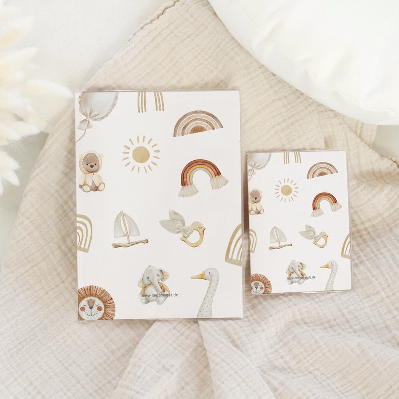 May include: Two printable sheets with a white background and a repeating pattern of illustrations. The illustrations include a sun, a rainbow, a sailboat, a bird, a bear, an elephant, a lion, and a goose. The text "www.mejsjilda.de" is printed on the sheets.