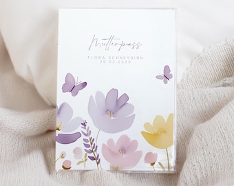Puede incluir: Una tarjeta blanca con el texto "Mutterpass" y "FLORA SCHNEYDERN 20.02.2000" impreso en ella. La tarjeta está decorada con flores de estilo acuarela en tonos de morado, rosa y amarillo, y mariposas.