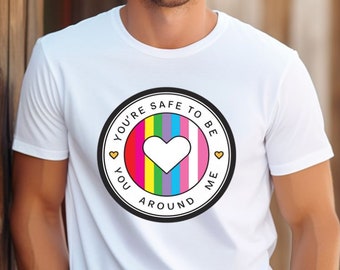 Puede incluir: Camiseta blanca con un gráfico en blanco y negro de un corazón arcoíris con el texto "You're safe to be around me".