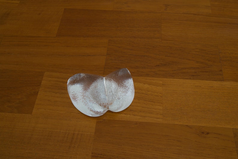 May include: Two silver-colored, heart-shaped ice molds on a wooden surface.