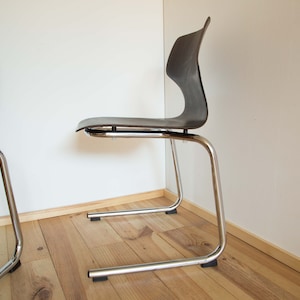 May include: Two black and chrome dining chairs with a curved back and a simple design.