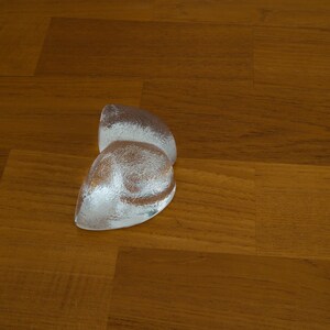May include: A pair of clear glass paperweights in the shape of a heart, sitting on a wooden surface.