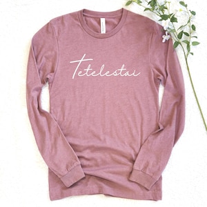 May include: A white ceramic mug with a black handle and the text "But First, Coffee" in a handwritten style. The mug is on a white surface.