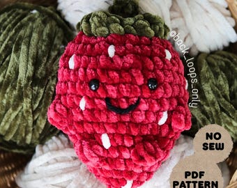 Puede incluir: Una fresa de ganchillo roja con detalles de semillas blancas, ojos negros y una boca sonriente. Tiene una parte superior verde con hojas. La imagen incluye el texto "NO SEW" y "PDF PATTERN".