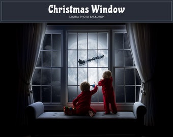 May include: Two children in red pajamas look out a window at a full moon with Santa Claus flying in his sleigh. The window is framed by white curtains and a dark gray couch.