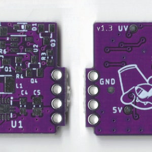 May include: A purple circuit board with a white chip labeled "U1" and various components, including resistors, capacitors, and a chip labeled "U2". The board has a white outline of a cartoon animal wearing a hat and sunglasses.