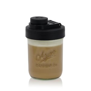 May include: A clear glass jar filled with a light brown liquid, topped with a black lid. The lid has a star design and a flip-top opening. The jar has the embossed text "Acure Canning Co."