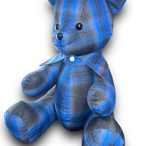 May include: A blue and black plaid teddy bear with a white button on its shirt.
