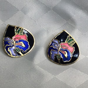 Stunning golden partitioned earrings with an orchid on a black background.