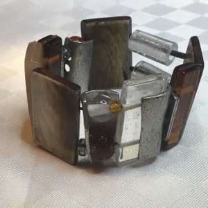 Anne Marie Chagnon. Beautiful elastic bracelet made of glass horn and tinplate in shades of brown and beige.