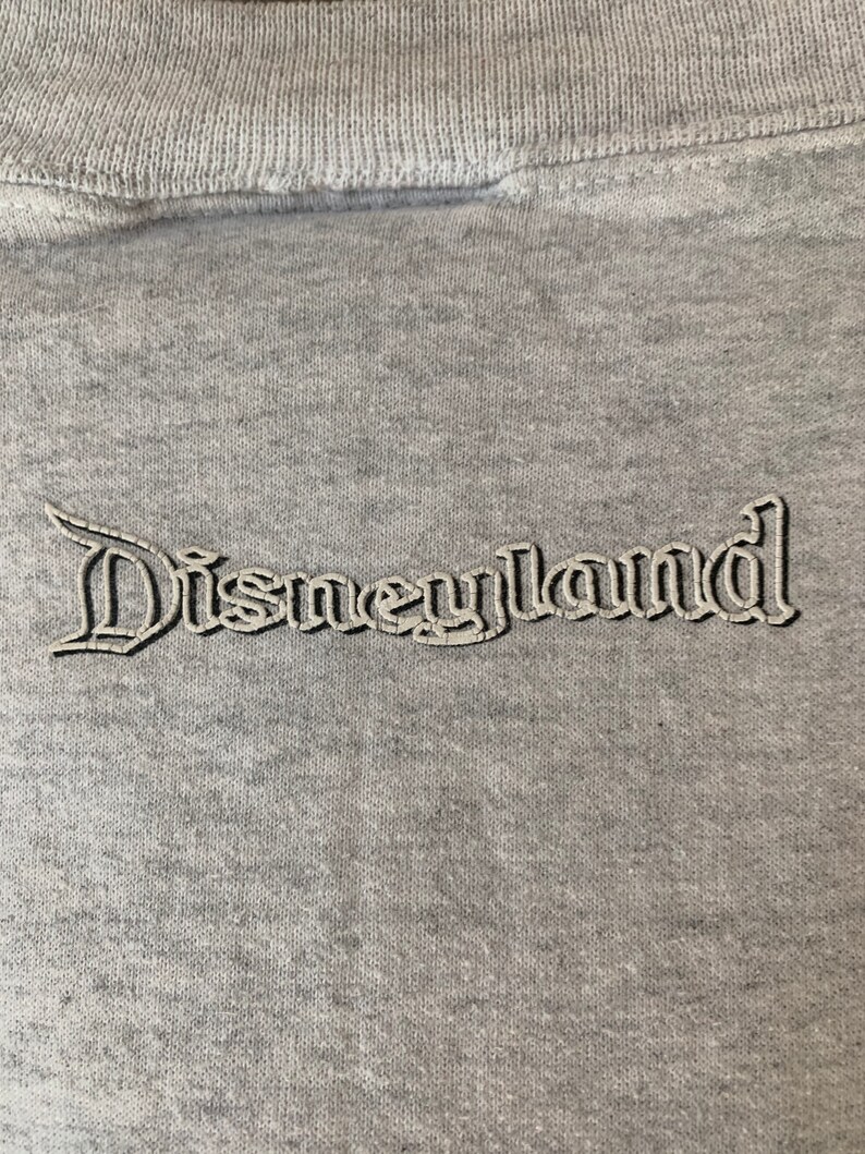 May include: Gray sweatshirt with a white embroidered Disneyland logo.
