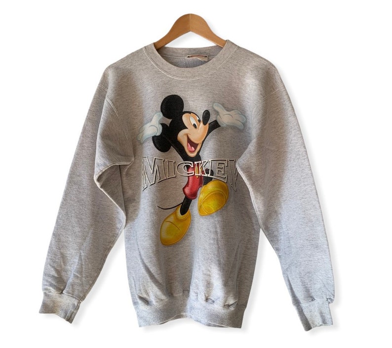May include: A gray sweatshirt with a vintage Mickey Mouse graphic and the word "Mickey" printed in silver lettering.