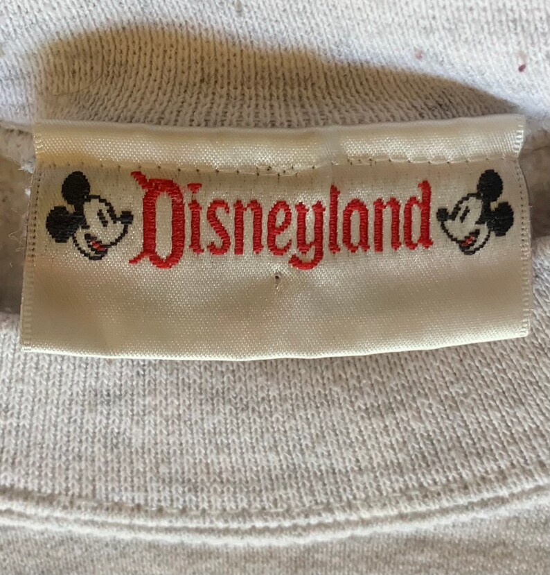 May include: White label with red embroidered text "Disneyland" and Mickey Mouse heads on either side.