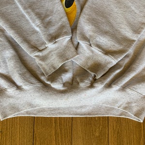 May include: Gray sweatshirt with ribbed cuffs and waistband. The sweatshirt is made of a soft, comfortable material.