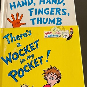May include: A yellow book with the title "There's a WOCKET in my POCKET!" in blue text. A boy with brown hair and a red shirt is looking over his shoulder. A green creature with yellow hair is in the bottom left corner. The book has a sticker that says "BRIGHT & EARLY BOOKS for BEGINNING READERS".