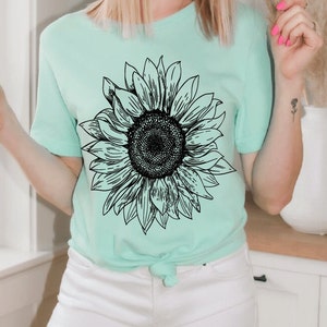 May include: A light green t-shirt with a black and white graphic of a sunflower.