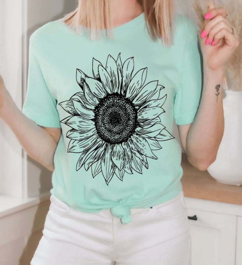 May include: A light green t-shirt with a black and white graphic of a sunflower.