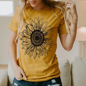 May include: A mustard yellow t-shirt with a black and white line drawing of a sunflower.