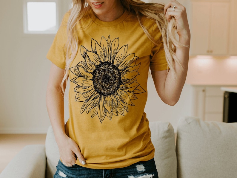 May include: A mustard yellow t-shirt with a black and white line drawing of a sunflower.