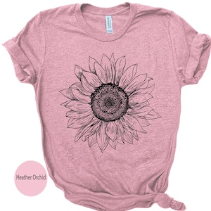 May include: A heather orchid colored t-shirt with a black and white line drawing of a sunflower.