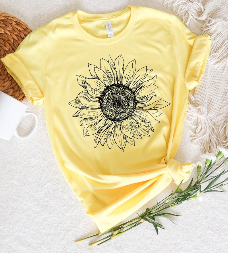 May include: A yellow t-shirt with a black and white line drawing of a sunflower.