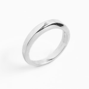May include: A polished, silver ring with a smooth, curved design. The ring has a simple, elegant style, and is set against a white background. The ring is a piece of jewellery.