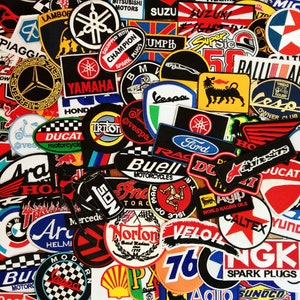 May include: A collection of colorful embroidered patches featuring various motorcycle and automotive brands, including Yamaha, Honda, Ducati, Suzuki, and Vespa. The patches are arranged in a random pattern and are all different sizes and shapes.