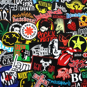 Op de afbeelding: Een verzameling kleurrijke strijklabels met verschillende rockbandlogo's, waaronder Nirvana, Green Day, Red Hot Chili Peppers, Pearl Jam en Blink-182. De labels zijn in een willekeurig patroon gerangschikt en zijn allemaal in verschillende maten en vormen.