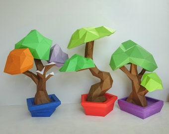 May include: Three origami bonsai trees in different colors, including orange, green, and purple. The trees are made of paper and have brown paper trunks. Each tree is in a pot, with the pots being blue, red, and purple.