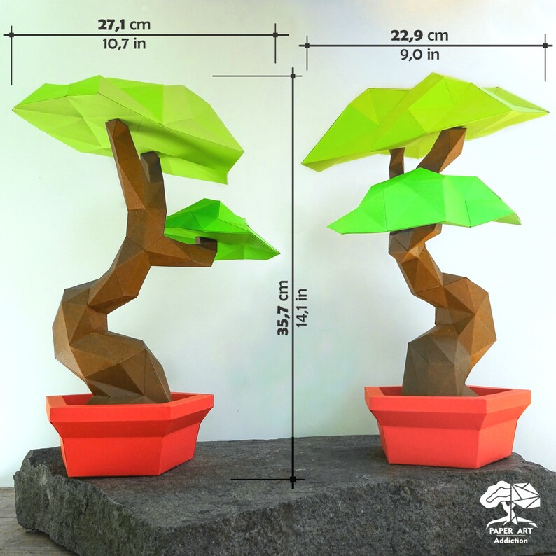 May include: Two origami bonsai trees, each in a red pot, sit on a stone surface. The trees are brown with green foliage. The left tree is 10.7 inches wide and 14.1 inches tall. The right tree is 9.0 inches wide. The text "PAPER ART Addiction" is in the lower right.