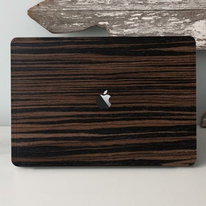 May include: A black and brown wood-grain laptop skin with the Apple logo in the centre.