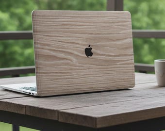 Puede incluir: Un portátil con una cubierta con textura de madera y un logotipo negro de Apple está sobre una mesa de madera. Una taza beige está a la derecha del portátil. El fondo muestra una escena exterior verde borrosa.