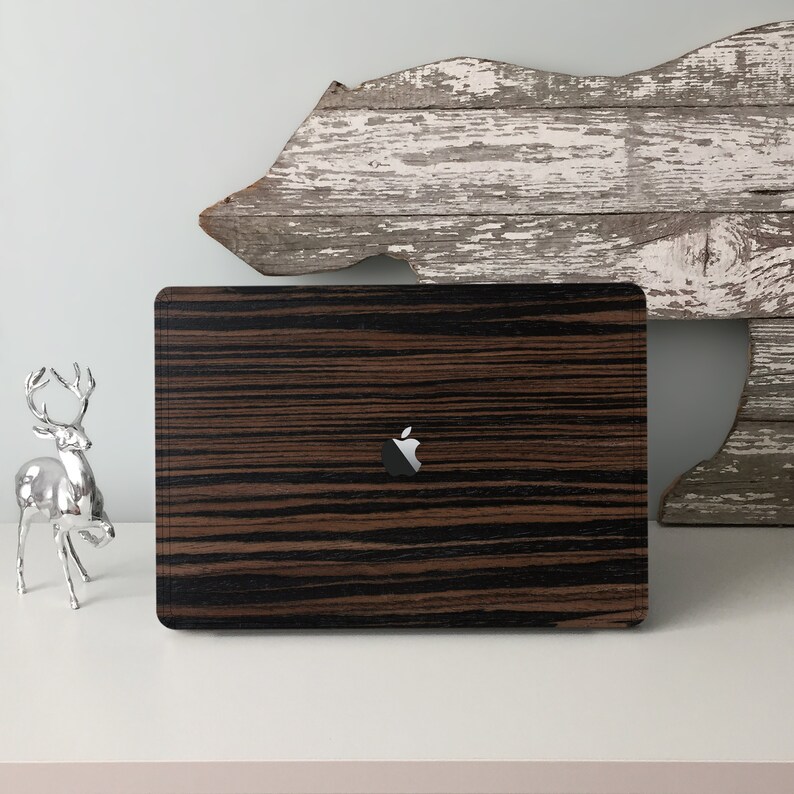 May include: A black and brown wood-grain laptop skin with the Apple logo in the centre.