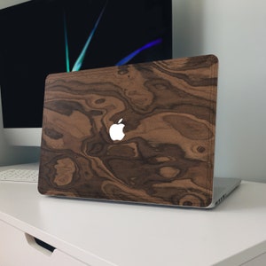 May include: A laptop computer with a wood grain design on the lid. The lid has a white Apple logo in the center.