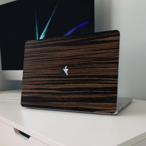 May include: A closed laptop computer with a wood grain design on the lid. The laptop has a silver Apple logo on the lid.
