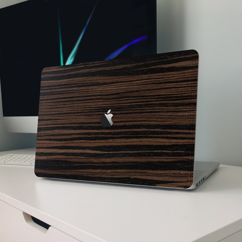 May include: A closed laptop computer with a wood grain design on the lid. The laptop has a silver Apple logo on the lid.